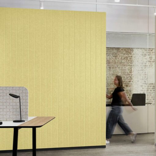 Woven image longitude acoustic panels in yellow in office space with woman walking past